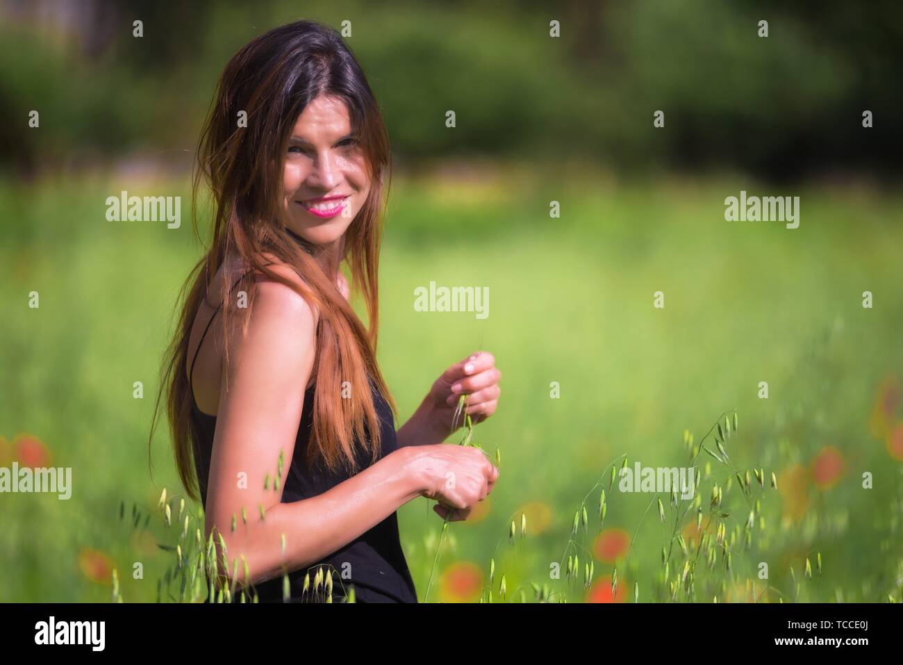 Schöner Frühling junge Frau im Freien die Natur genießen. Gesunde lächelnde Mädchen in Blüte Frühling Wiese. Stockfoto