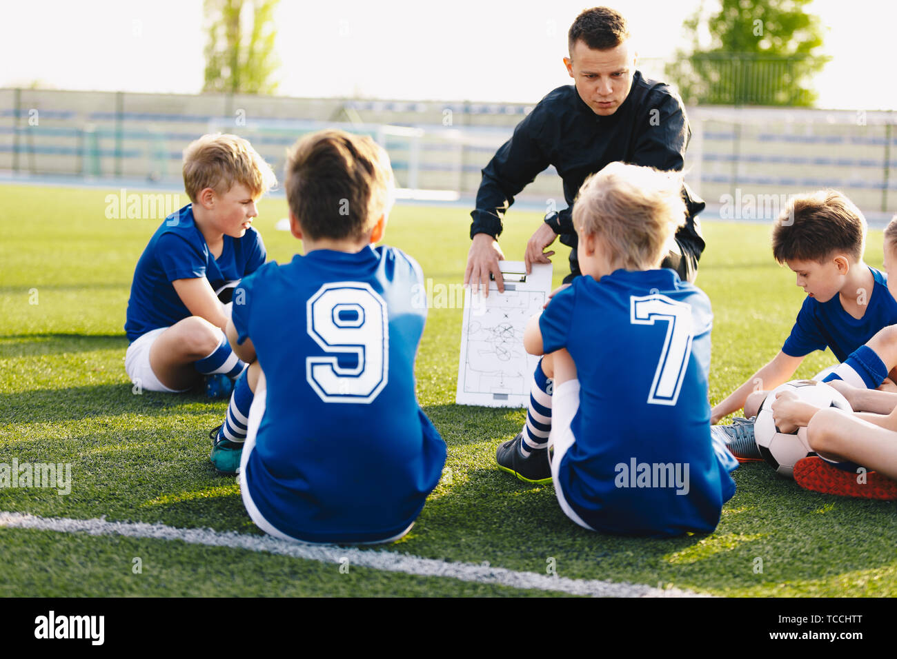 Fußball-Trainer coaching Kids. Fußball-Fußball-Training für junge Jungen. Junge Trainer Unterrichten von Kindern am Fußballplatz. Fußball Taktik educat Stockfoto