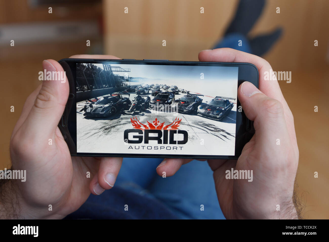 LOS ANGELES, Kalifornien - Juni 3, 2019: Lügen Mann hält ein Smartphone und Spielen der GRID Autosport Spiel auf den Bildschirm des Smartphones. Eine illustrative e Stockfoto