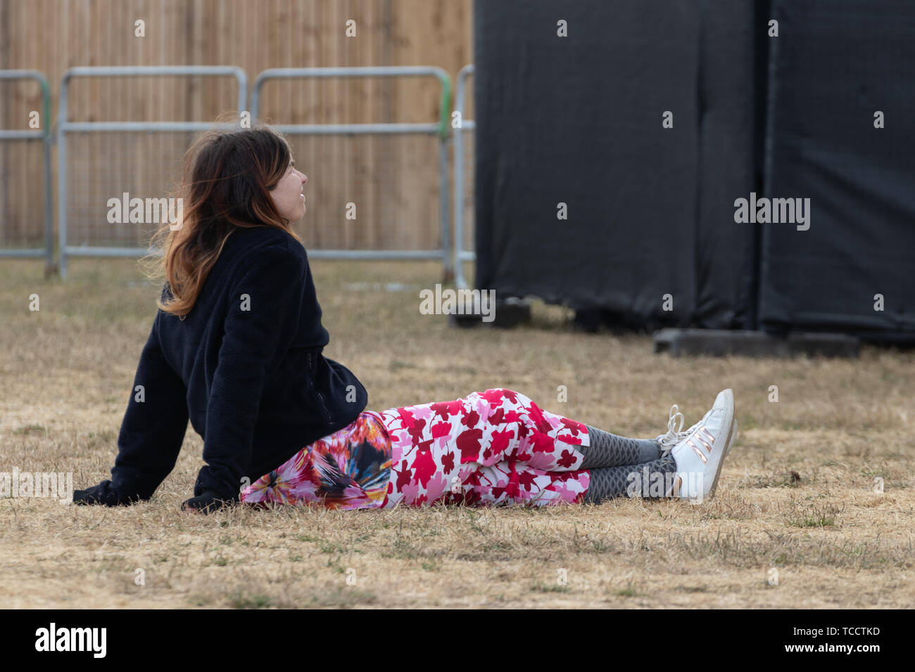 Eine Frau saß auf dem Gras an einem Open Air Festival die Show genießen Stockfoto