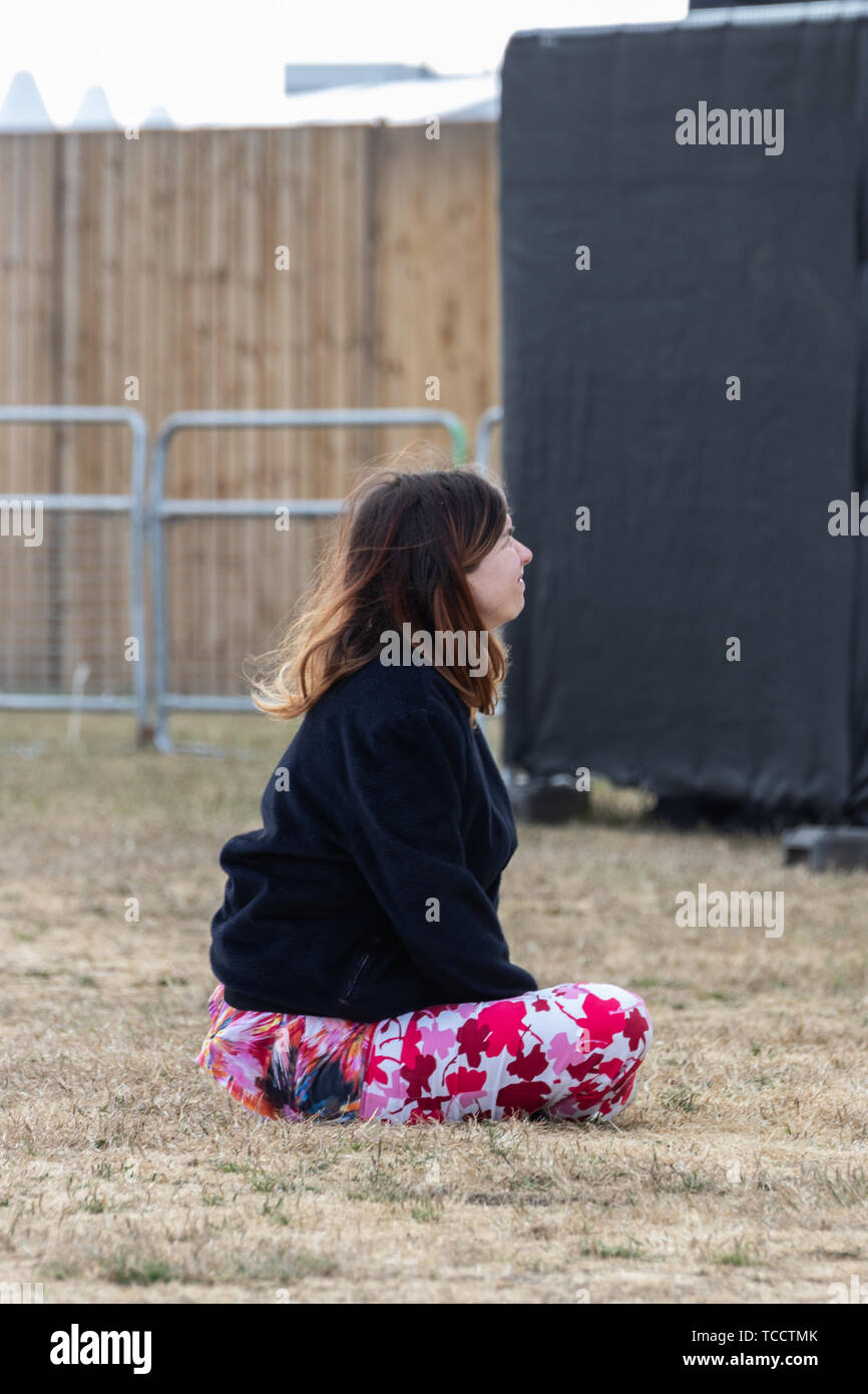 Eine Frau saß auf dem Gras an einem Open Air Festival die Show genießen Stockfoto
