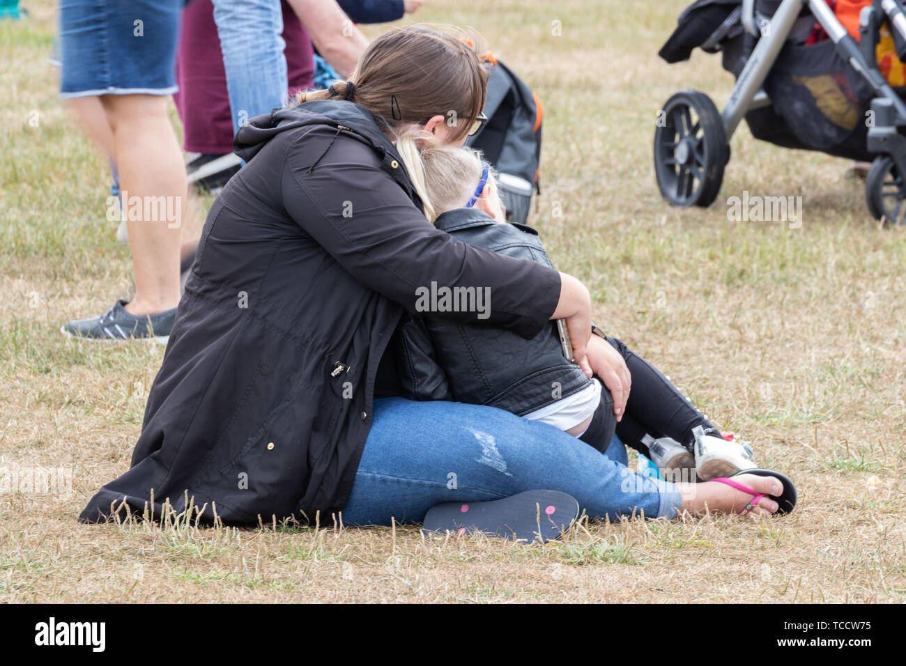 Eine Mutter saß auf dem Gras mit ihrer Tochter umarmen Stockfoto