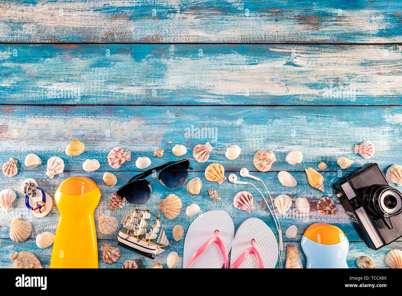 Strand Zubehör retro Film Kamera Sonnenbrillen flip flop und Sea Shell auf Holz. Blick von oben auf den Strand Zubehör auf Blau plank Sommerurlaub banner tr Stockfoto