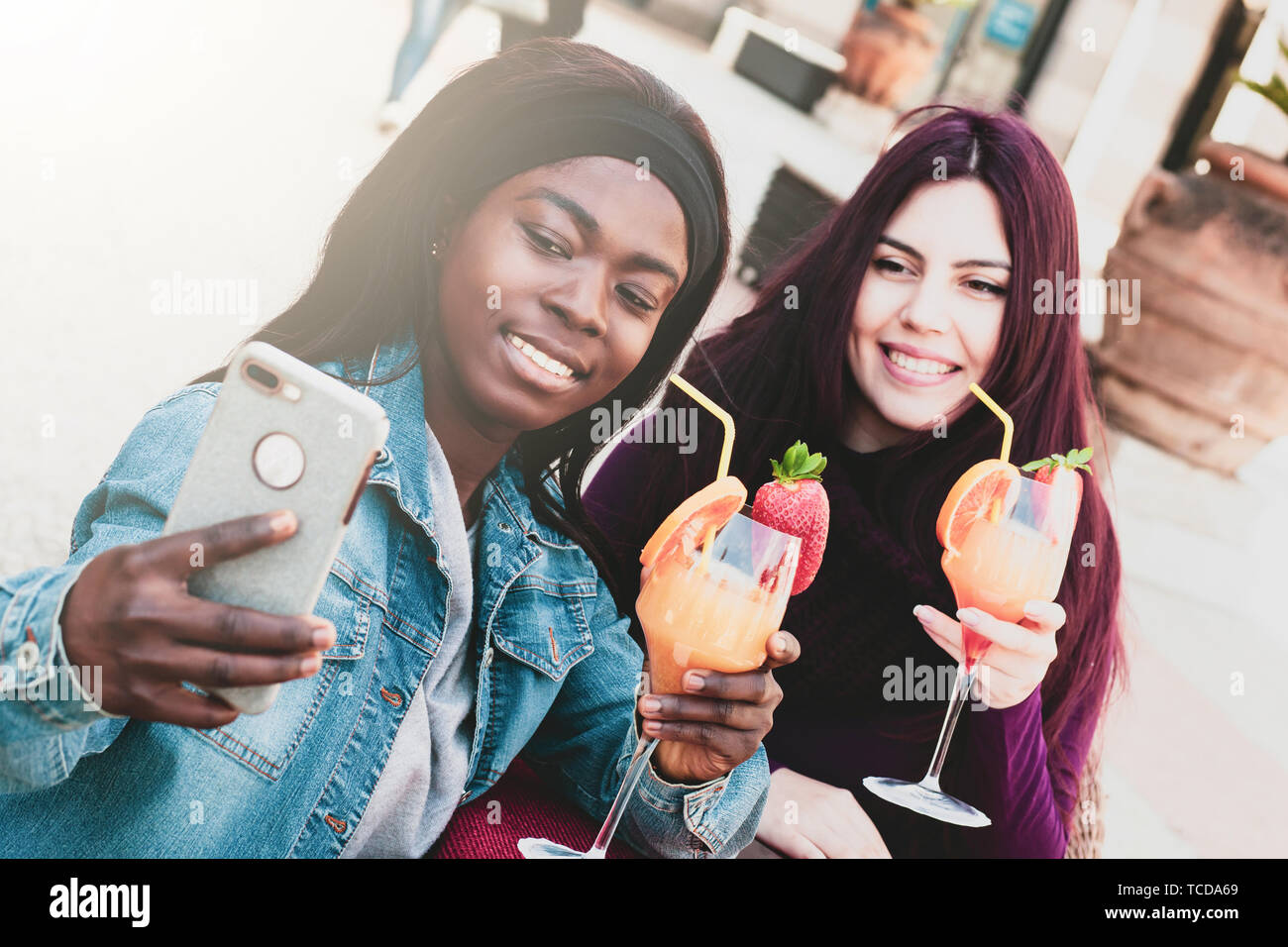 Zwei Freunde, einer kaukasischen und einem Afrikanischen, selfie während Cheers mit Cocktails. Stockfoto