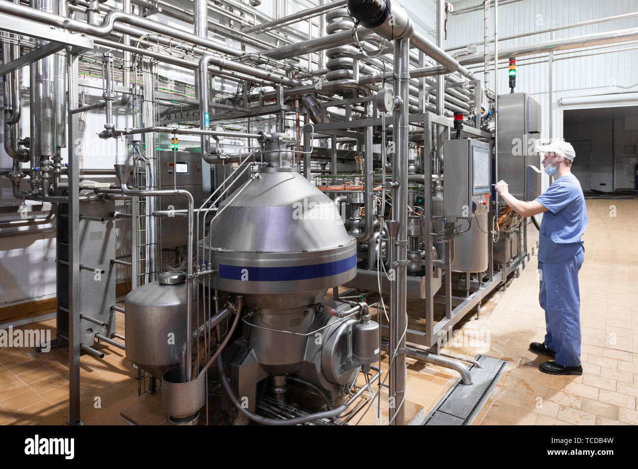 Arbeiter in eine blaue Robe und eine Kappe prüfen Sie die Produktion der Molkerei Stockfoto