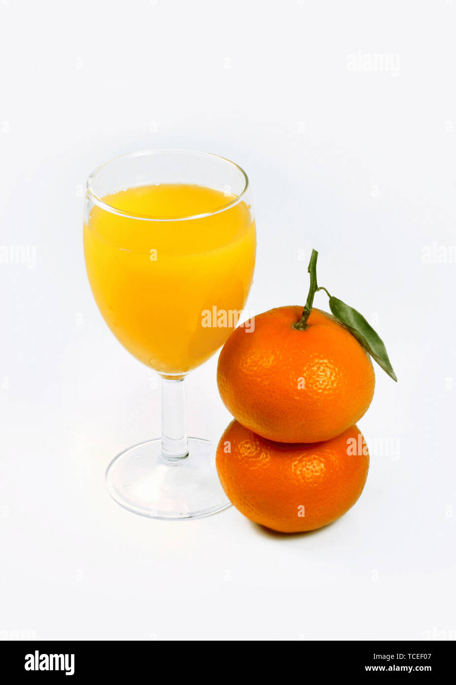 Zitronensaft und zwei Mandarinen auf weißem Hintergrund Stockfoto