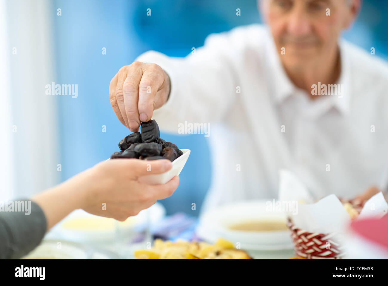 Moderne multiethnischen muslimische Familie teilen eine Schüssel Termine beim Iftar gemeinsam das Abendessen genießen, während des Ramadan Fest zu Hause Stockfoto