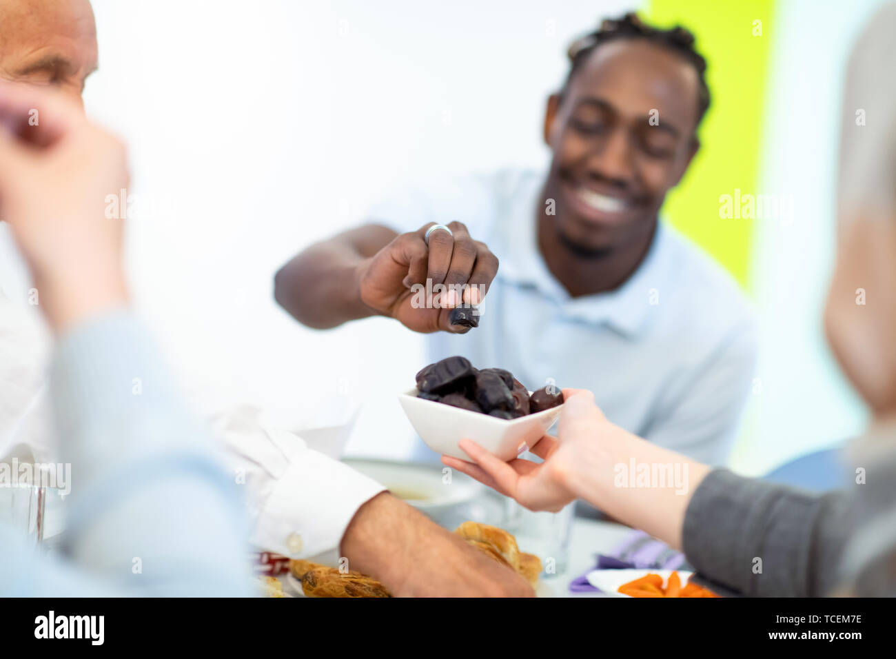 Moderne multiethnischen muslimische Familie teilen eine Schüssel Termine beim Iftar gemeinsam das Abendessen genießen, während des Ramadan Fest zu Hause Stockfoto
