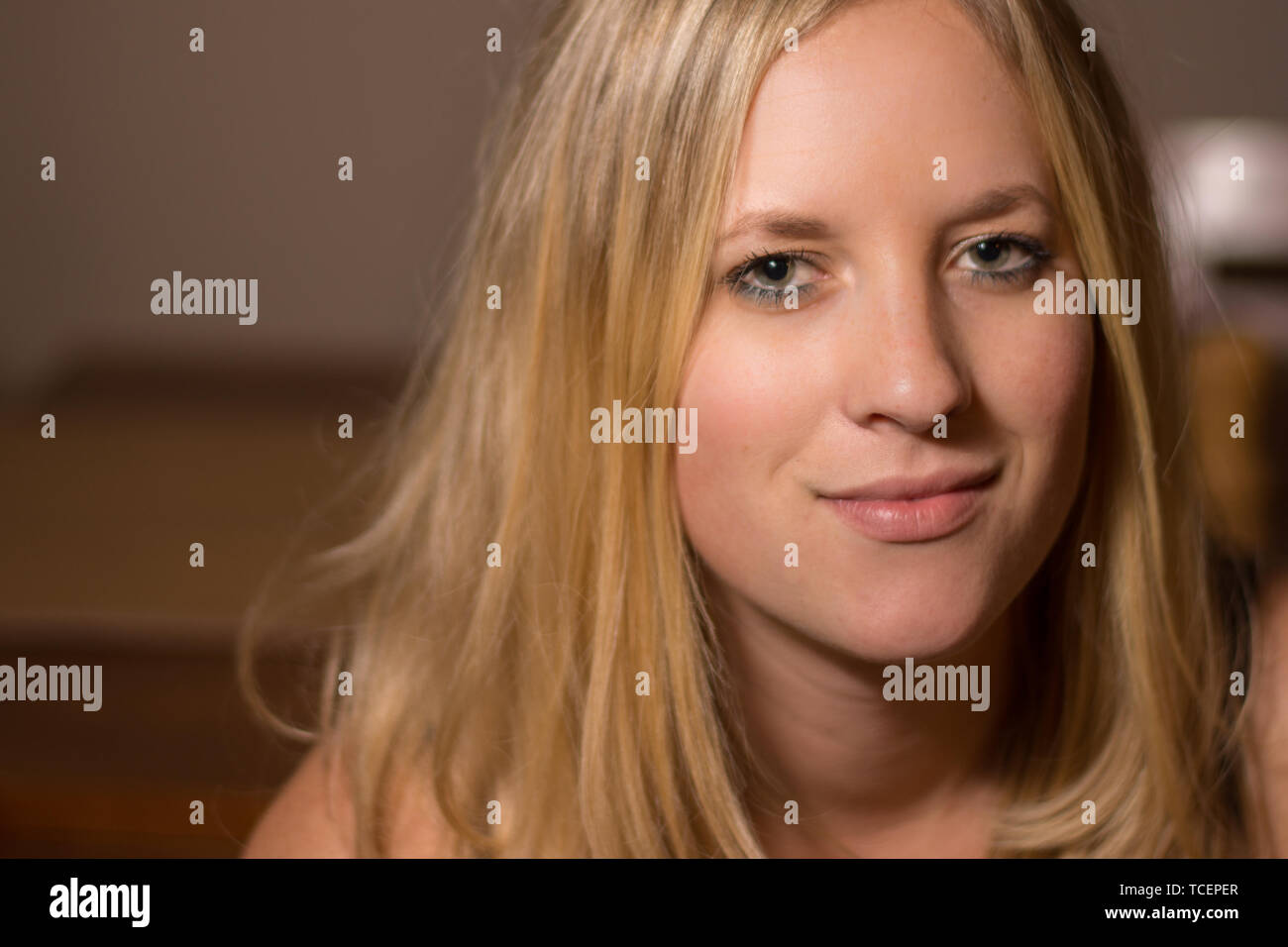 Eine blonde junge Frau Frauen Kopf geschossen mit einem schüchternen Lächeln und natürliches Aussehen. Stockfoto