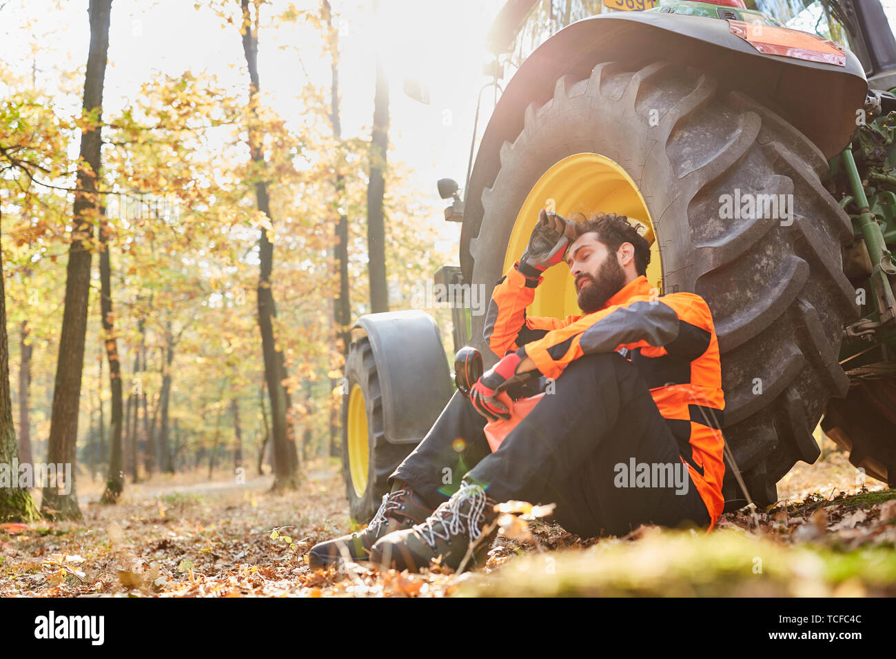 Erschöpfte Waldarbeiter nimmt einen Bruch mit dem Traktor in den Wald Stockfoto