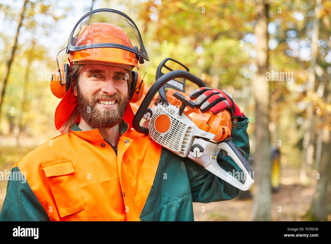 Holzfäller oder Waldarbeiter mit Motorsäge und Schutzausrüstung im Wald Stockfoto
