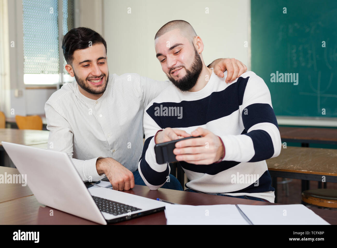 Zwei junge Studenten ablenken von ihren Studien und Beobachten bei Gadget Stockfoto
