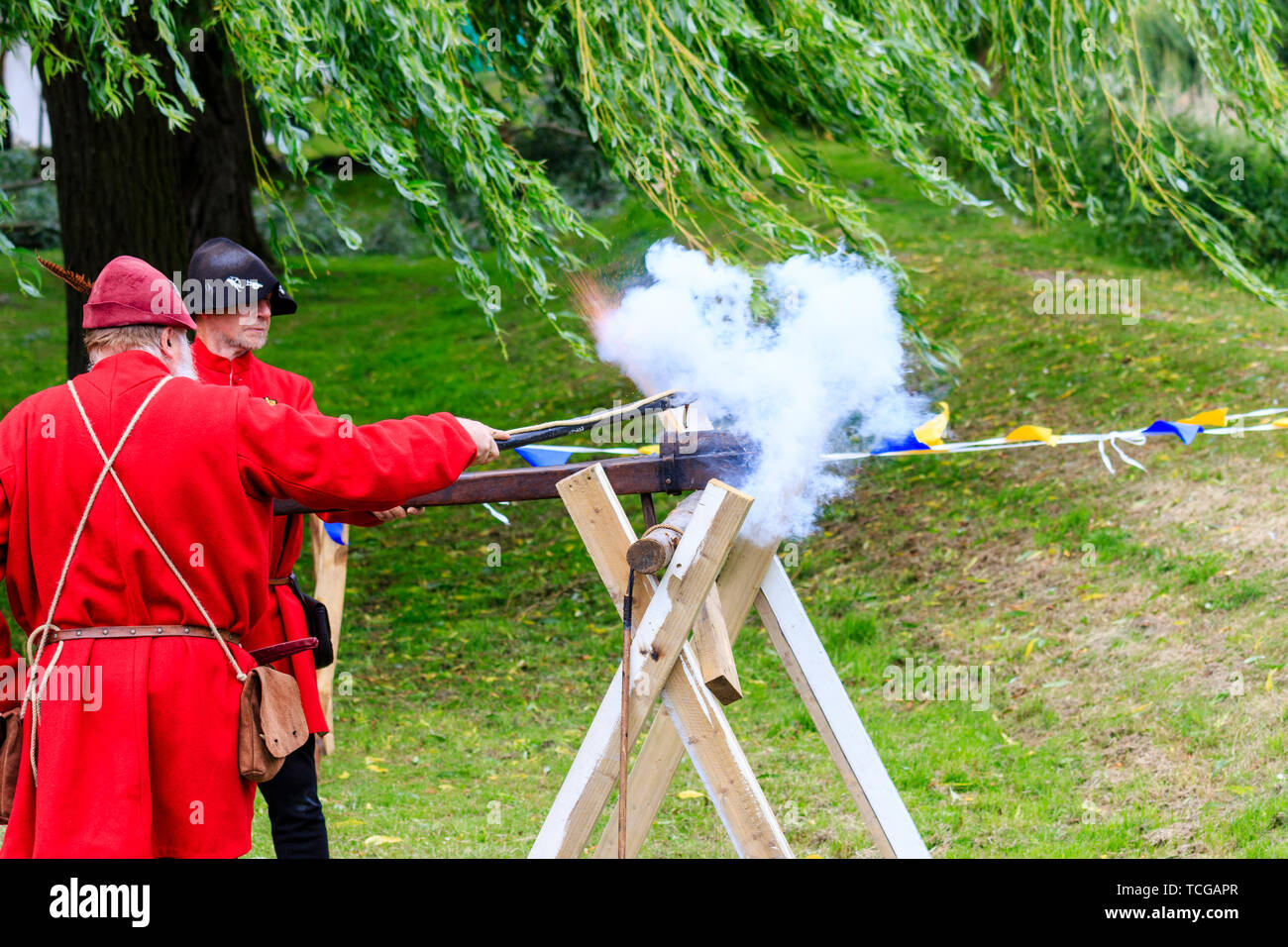 Le mittelalterliche Wochenende Re-enactment Veranstaltung am Sandwich Stadt in England. Mann gekleidet in mittelalterlichen Roten gunner Outfit und feuerte eine hand Cannon an einer Halterung montiert. Rauch und Feuer. Stockfoto