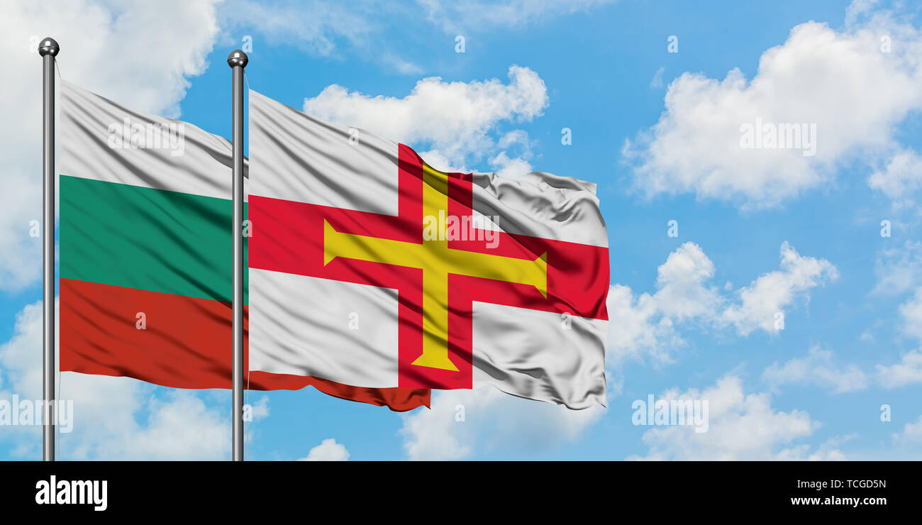 Bulgarien und Guernsey Flagge im Wind gegen Weiße bewölkt blauer Himmel zusammen. Diplomatie Konzept, internationale Beziehungen. Stockfoto