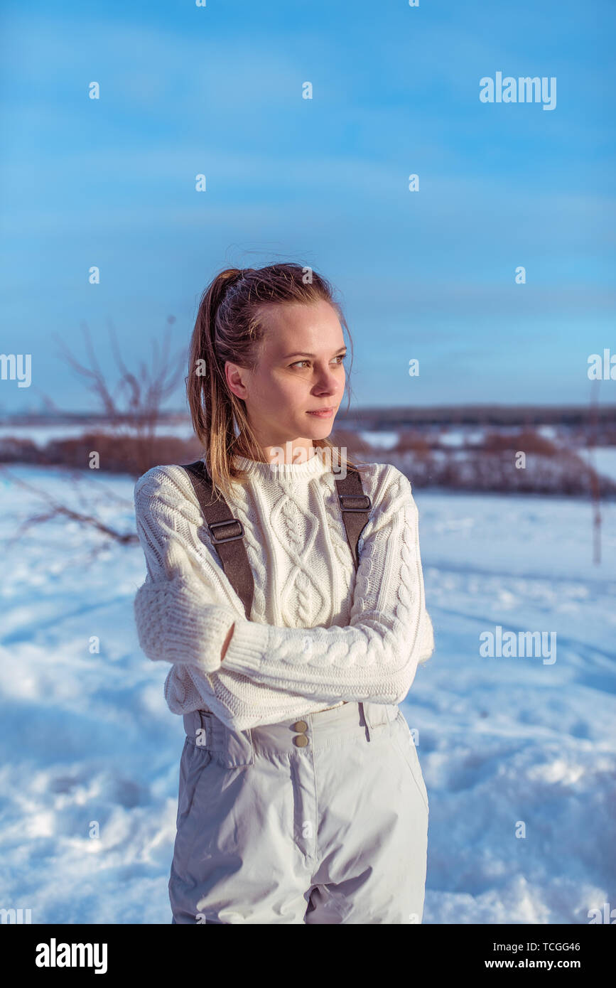 Mädchen in einem weißen Overall im Winter draußen, Hintergrund ist  Schneeverwehungen, in die Ferne suchen, einen warmen Pullover und weiße  Handschuhe. Das Konzept der Outdoor Stockfotografie - Alamy