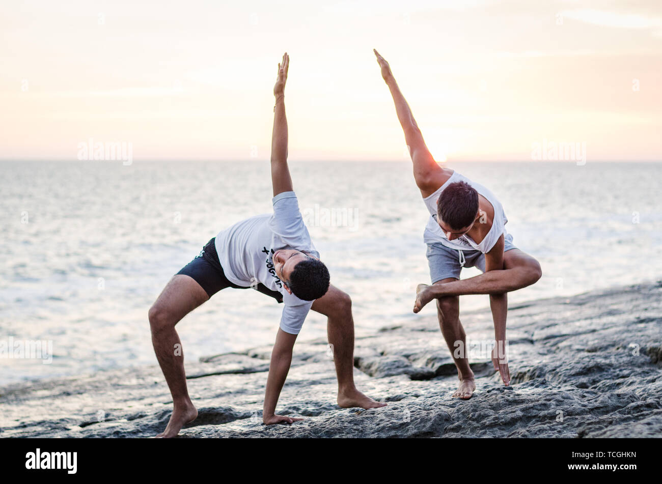 Zwei Freunde Üben Yoga am Rand des Ozeans bei Sonnenuntergang, Yoga oder Meditation Konzept Stockfoto