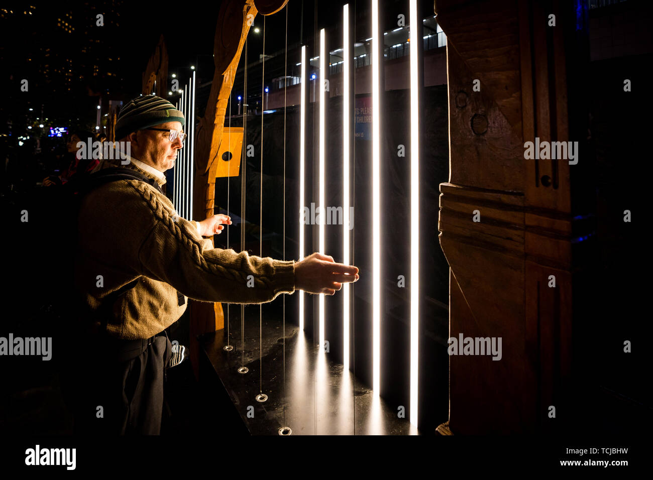 Ein Mann spielt eine Harfe mit hellem Display als Teil os Lebendige, Sydney's jährliche Licht Festival Stockfoto