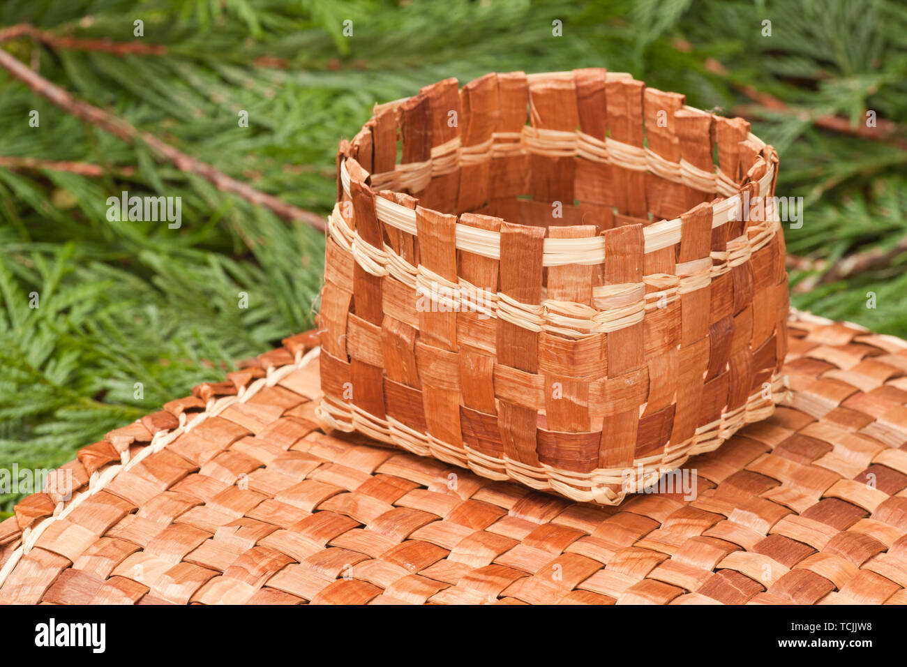 Hand-woven Matte und Korb aus der Pliant innere Rinde eines Western Red Cedar Baum gemacht, ruht auf Western Red Cedar branchlets. Stockfoto