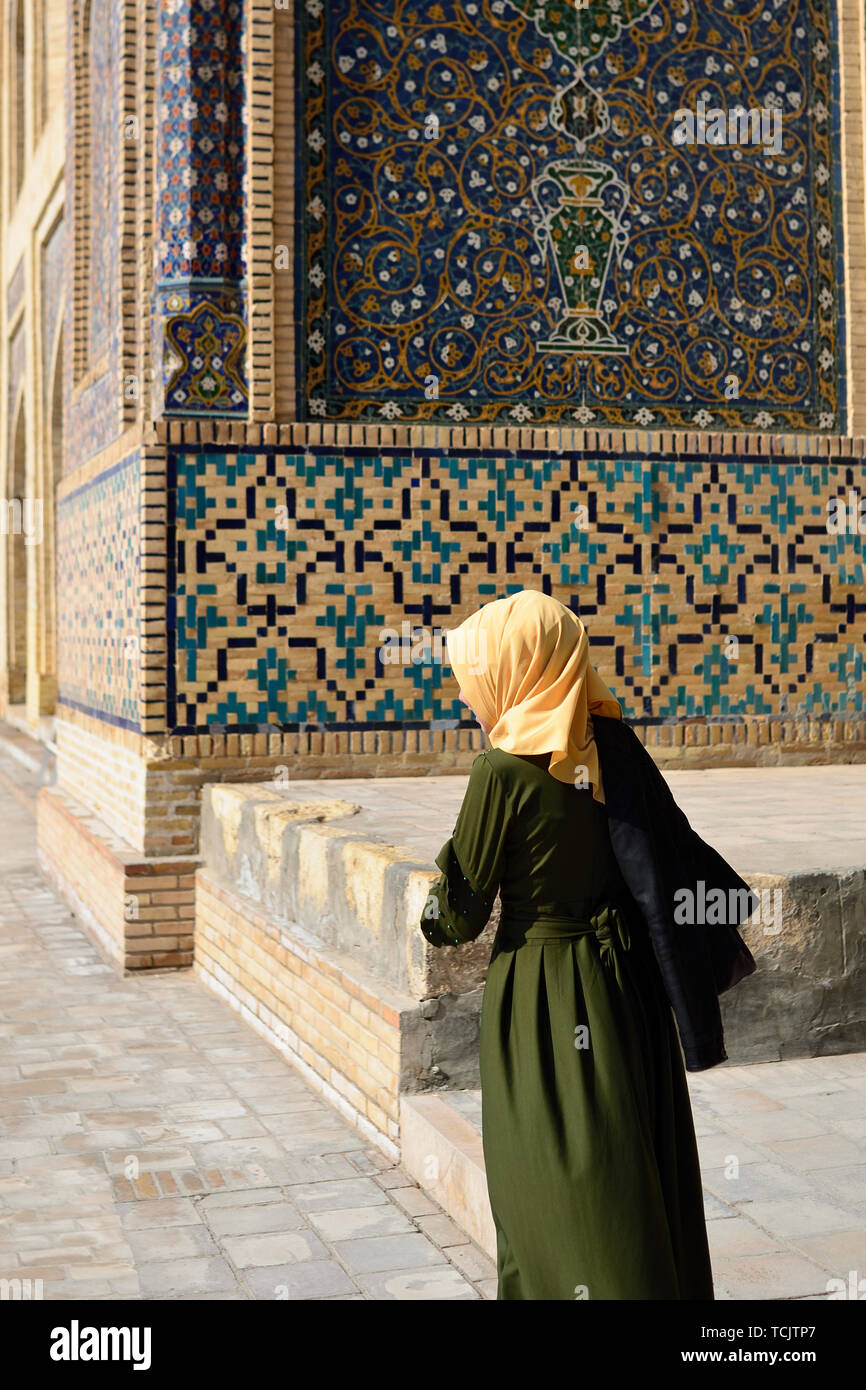 Die usbekische Frau in die traditionelle Kleidung auf dem Mosaik Hintergrund, Buchara, Usbekistan. Stockfoto