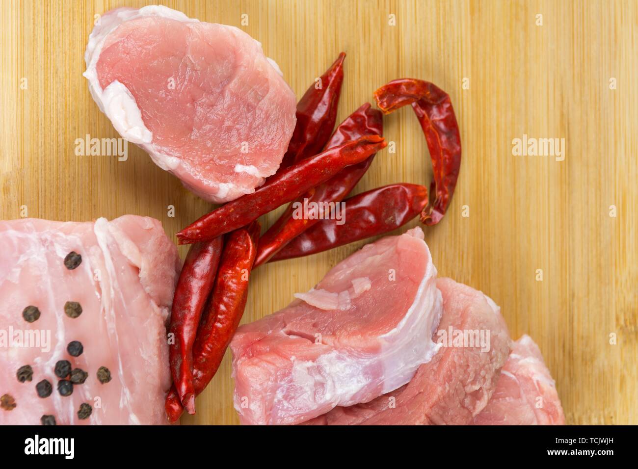 Raw Schweinekoteletts mit Gewürzen auf einem Holzbrett Stockfoto