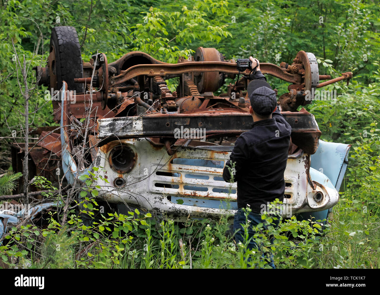 Ein Besucher nimmt Fotos eines havarierten auto in die Sperrzone von Tschernobyl in der verlassenen Stadt Pripyat. Die HBO-TV-Miniserie Tschernobyl, die Premiere in den USA und in England auf Mai 2019, zeigt die Zeit nach der Katastrophe, einschließlich der Reinigung und die anschließende Untersuchung. Der Erfolg HBO TV-Miniserie Tschernobyl Prüfung schlimmste Atomunfall von Tschernobyl hat sich die Anzahl der Touristen, die Anlage und die geisterhaften verlassenen Stadt, dass die Nachbarn es für sich selbst, und der Tourismus Industrie der Region beigetragen zu haben, mit den Chefs der Führungen zu Che zu sehen, angetrieben Stockfoto