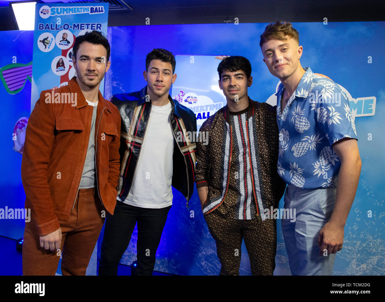 (Von links nach rechts) Kevin Jonas, Nick Jonas, Joe Jonas von den Jonas Brothers melden Sie Capital FM Moderator Roman Kemp im Studio während der Sommerzeit Ball. Größten Stars der Welt live für 80.000 Kapital Zuhörer im Wembley Stadion auf der größten Sommerfest in Großbritannien. Stockfoto