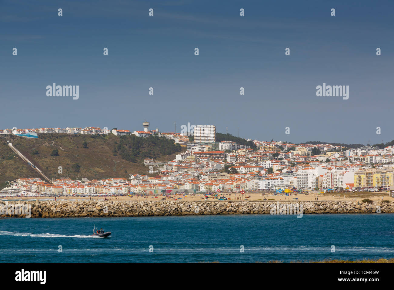 Blick von der Hafeneinfahrt von Fischerdorf Nazaré, Portugal mit kleinen Boot im Vordergrund Stockfoto