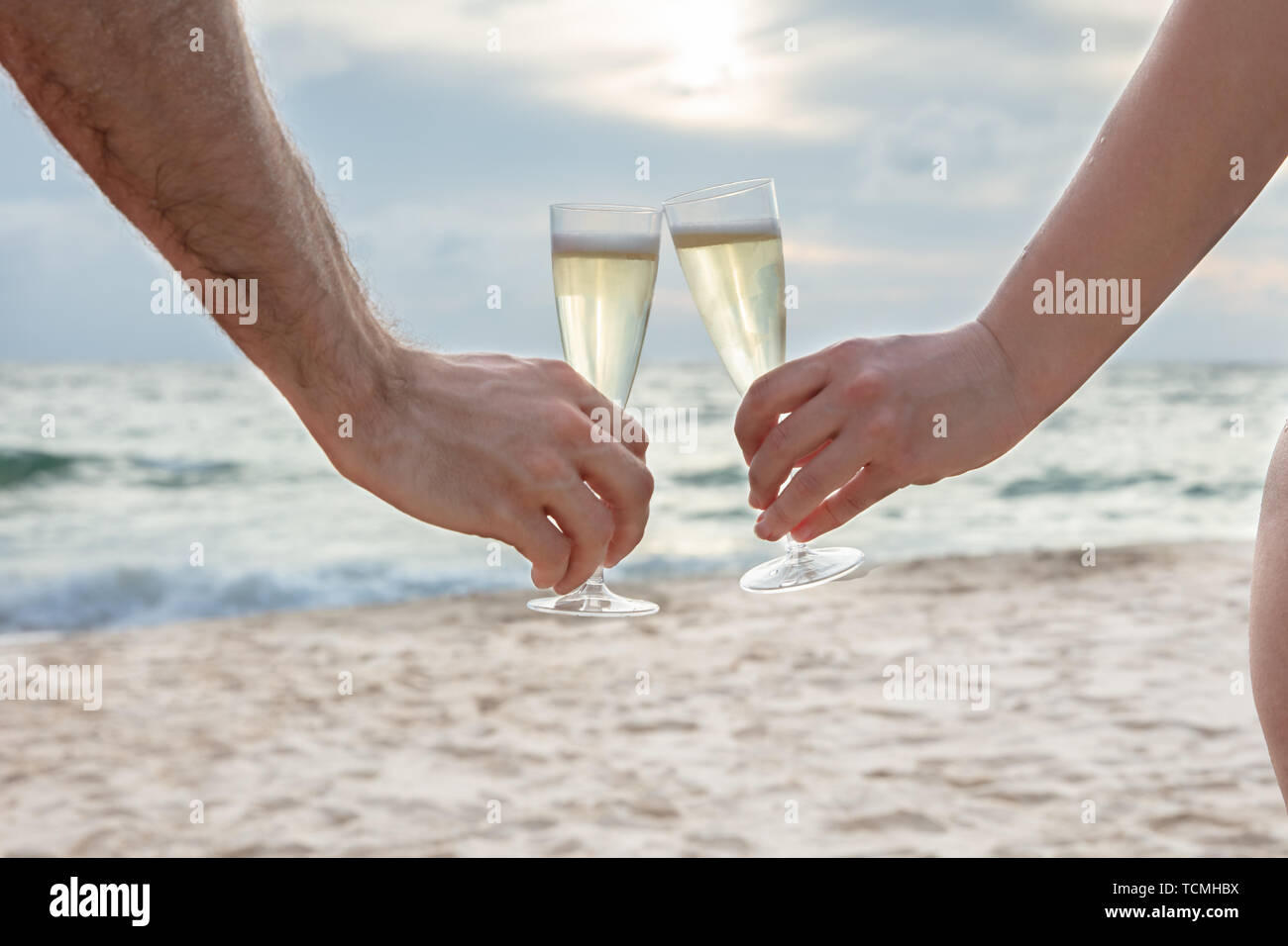 Nahaufnahme einer Person klirren Gläser Champagner in der Hand am Beach Stockfoto