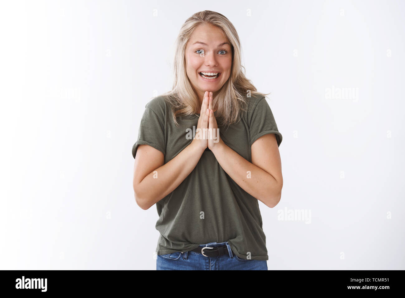 Charismatische cute Europäische Weiblich fragen Freund kleinen Gefallen Hände halten in Beten drücken Handflächen zusammen über den Körper lächelnd mit Engel Grinsen supplicat Stockfoto