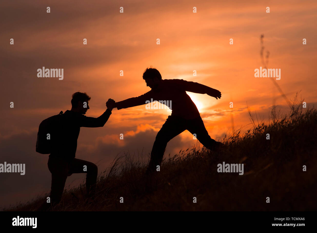 Teamarbeit von zwei Männern, die Wanderer, die sich gegenseitig helfen auf Bergsteigen Team, wunderschönen Sonnenuntergang Landschaft. Sport und aktiv leben Konzept Stockfoto