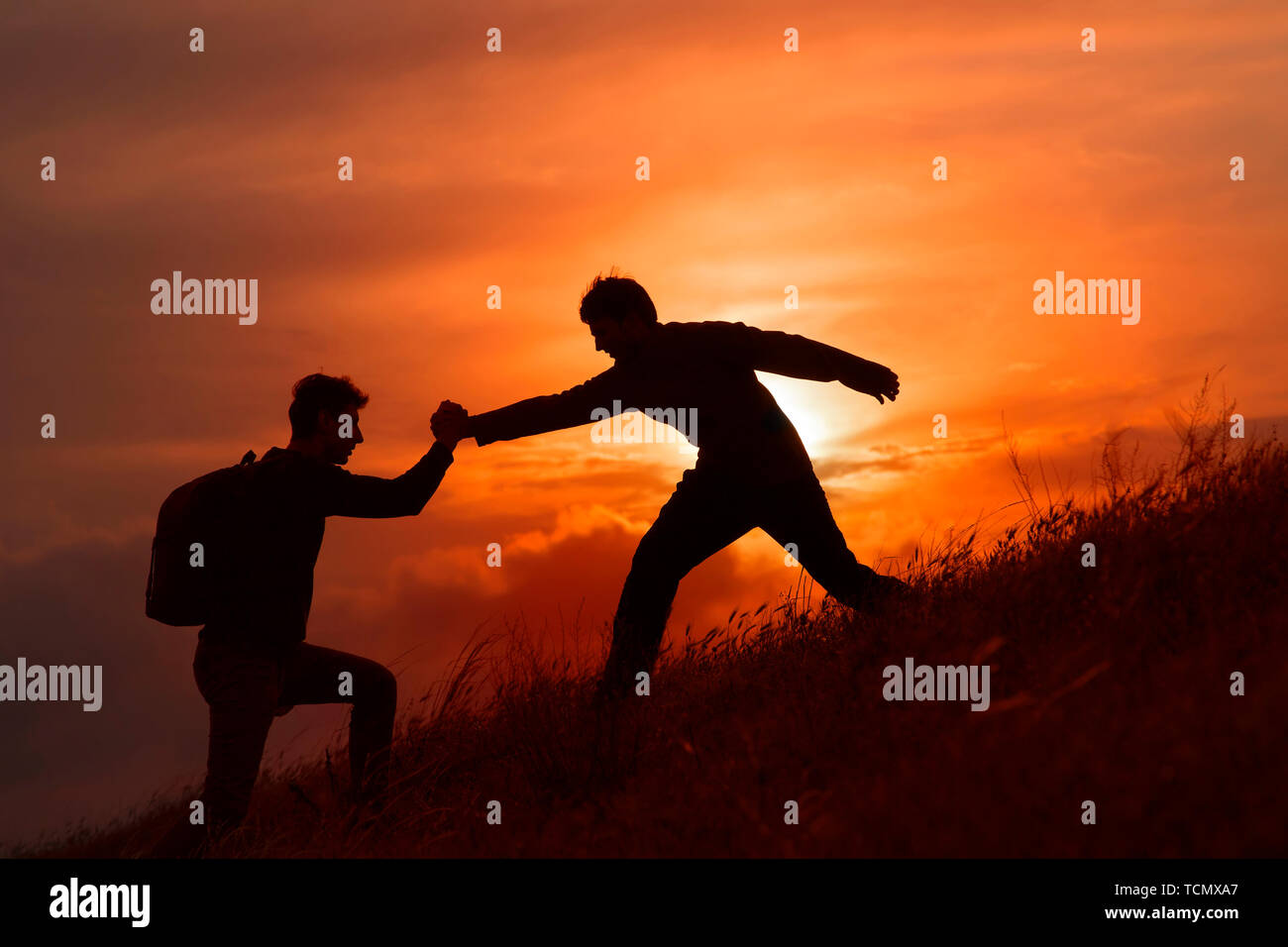 Teamarbeit von zwei Männern, die Wanderer, die sich gegenseitig helfen auf Bergsteigen Team, wunderschönen Sonnenuntergang Landschaft. Sport und aktiv leben Konzept Stockfoto