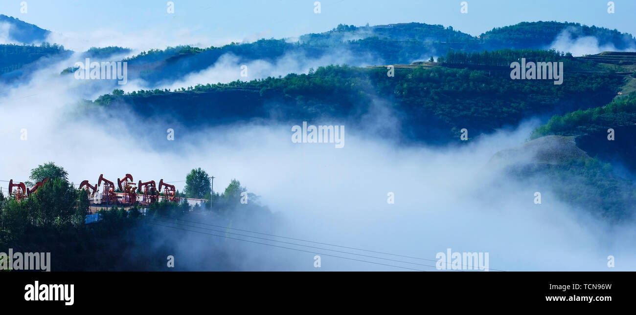 Yan'an, China. 8. Juni 2019. Foto am 8. Juni 2019 zeigt die fließende Wolken über Shengli Berg von Wuqi County in Yan'an City, im Nordwesten der chinesischen Provinz Shaanxi. Wuqi County hat eine Entwicklungspolitik seit 1998, dass Ackerland in Wald für Ökologischen Schutz und nachhaltige Entwicklung zurück. Credit: Zong Mingyuan/Xinhua/Alamy leben Nachrichten Stockfoto