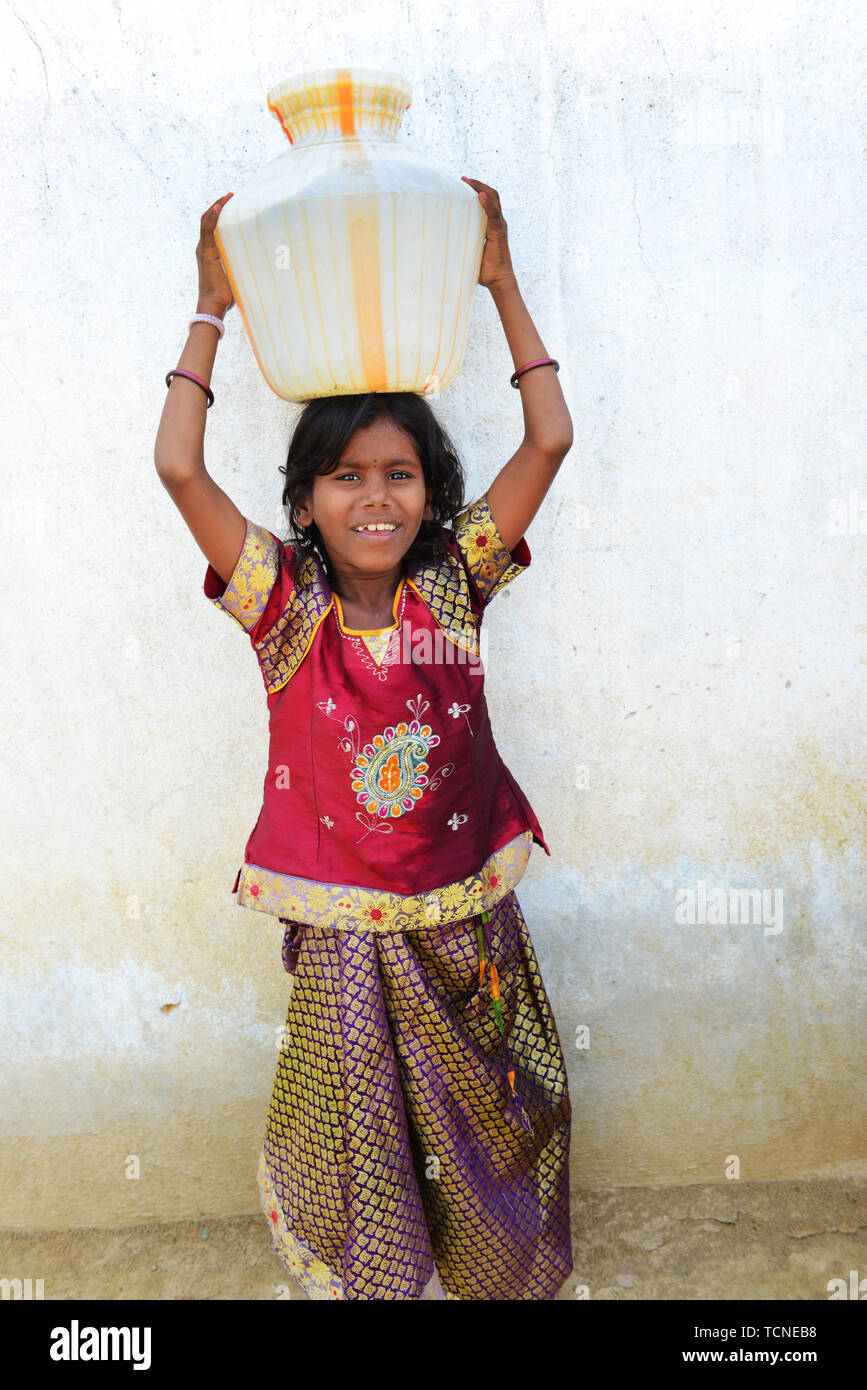 Eine tamilische Mädchen mit einem großen Wasserbehälter auf dem Kopf. Stockfoto