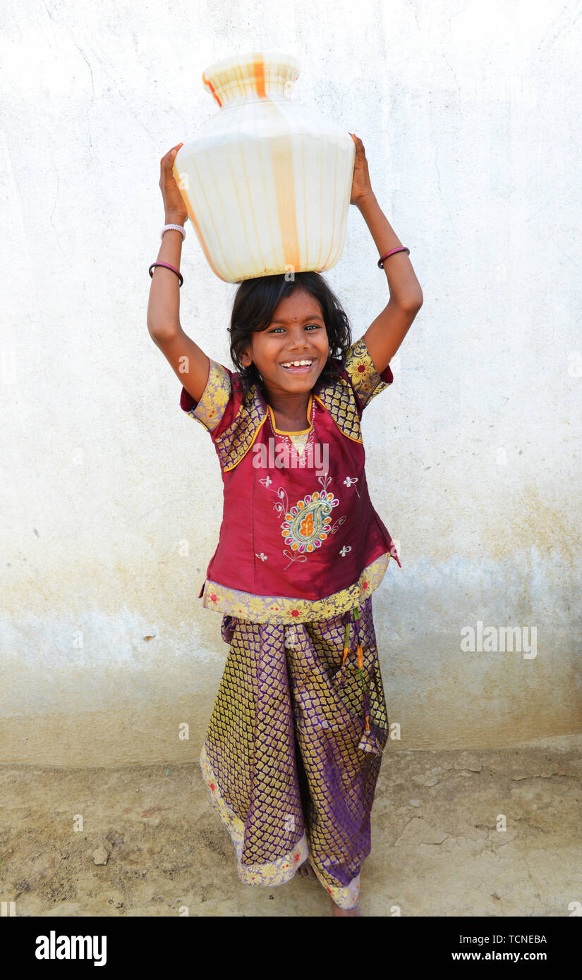 Eine tamilische Mädchen mit einem großen Wasserbehälter auf dem Kopf. Stockfoto