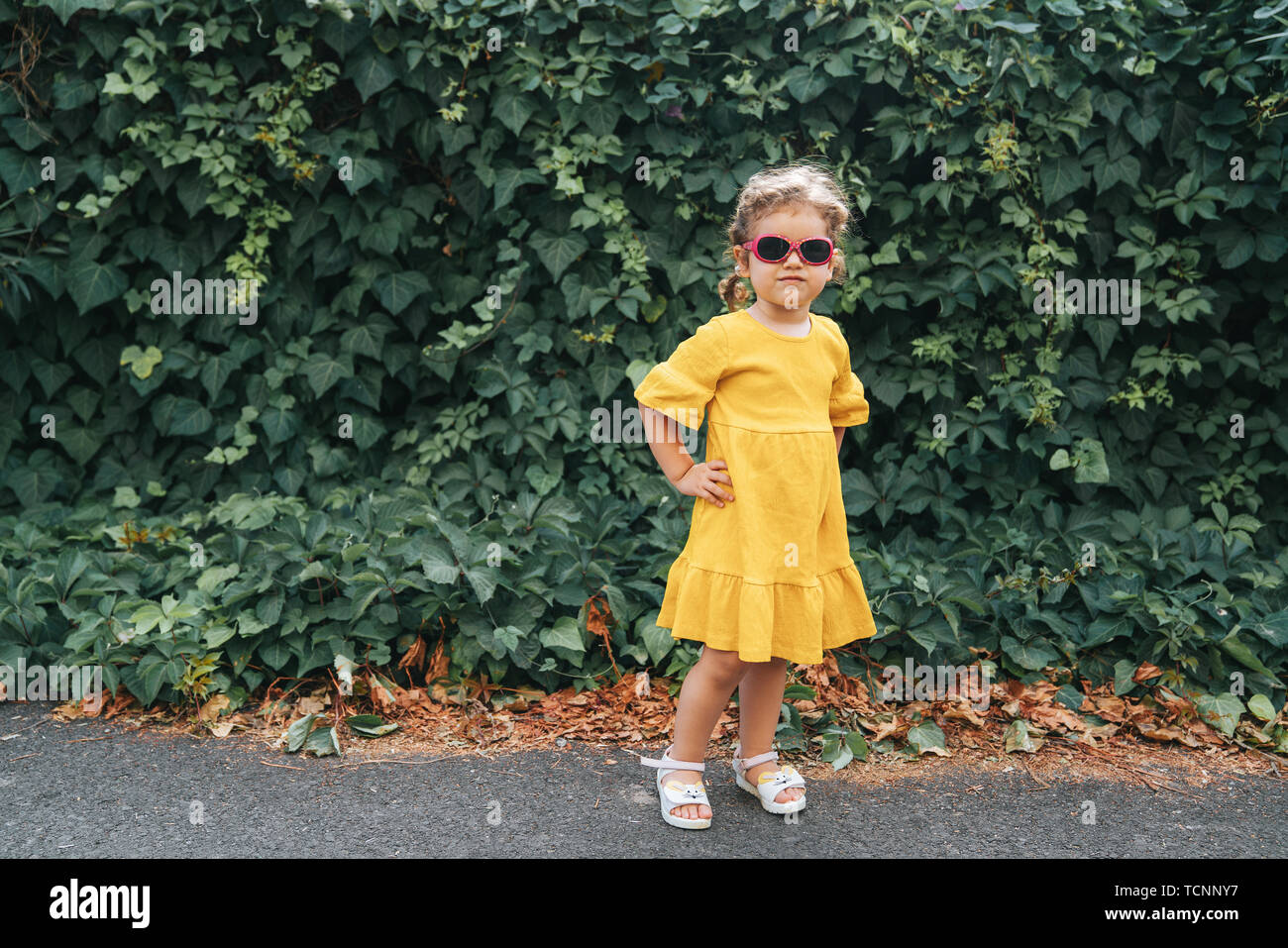 Portrait von Cute blonde Mädchen in der Kleidung posiert in sonniger Tag, und wenn man die Kamera im Freien Stockfoto