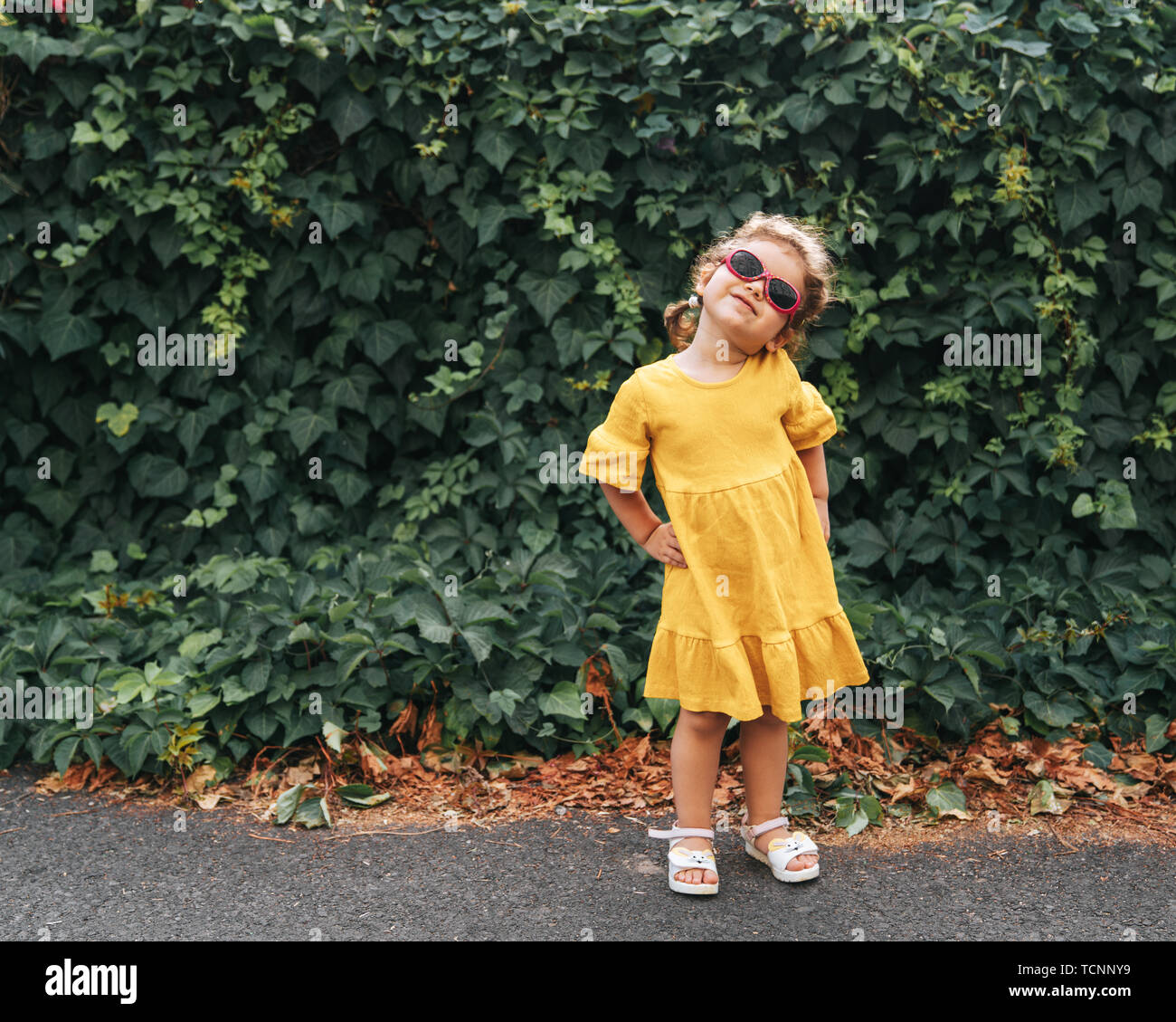 Portrait von Cute blonde Mädchen in der Kleidung posiert in sonniger Tag, und wenn man die Kamera im Freien Stockfoto