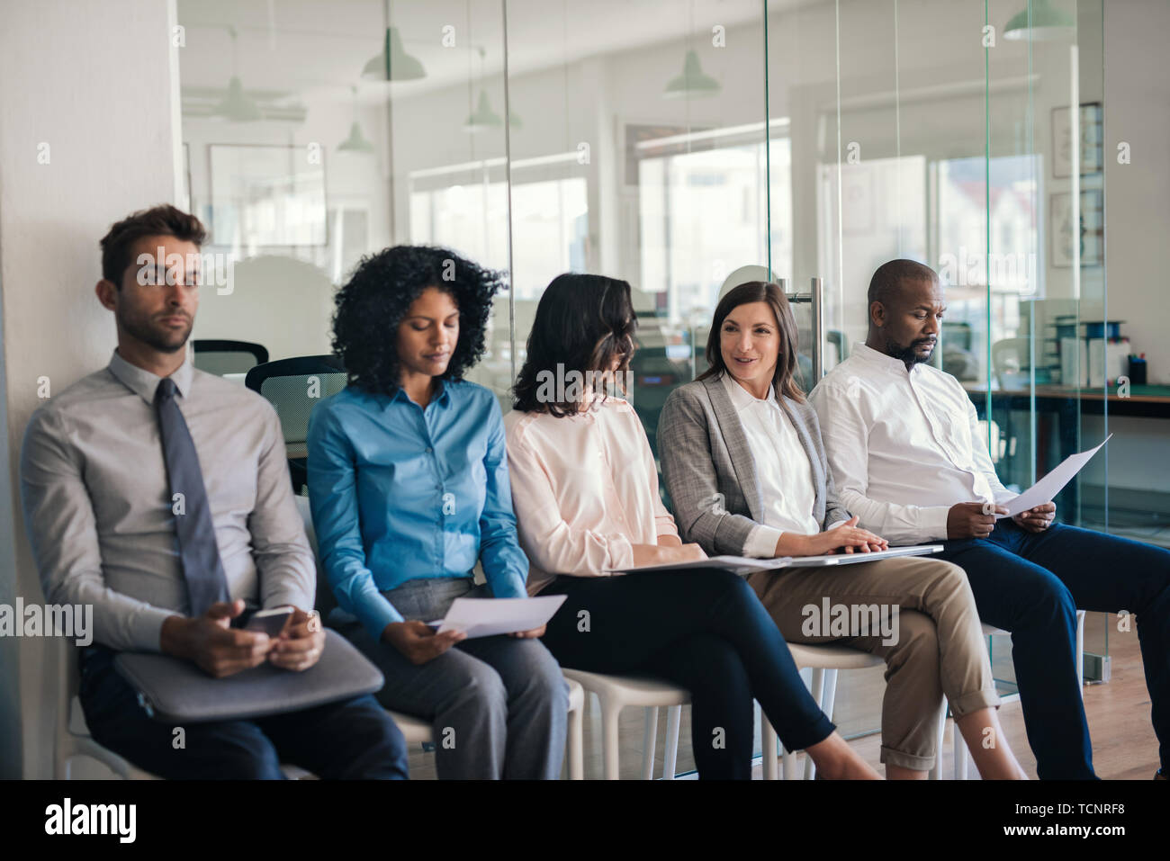 Vielfältige Gruppe von Bewerbern sitzen auf Stühlen außerhalb eines Büros warten interviewt zu werden Stockfoto
