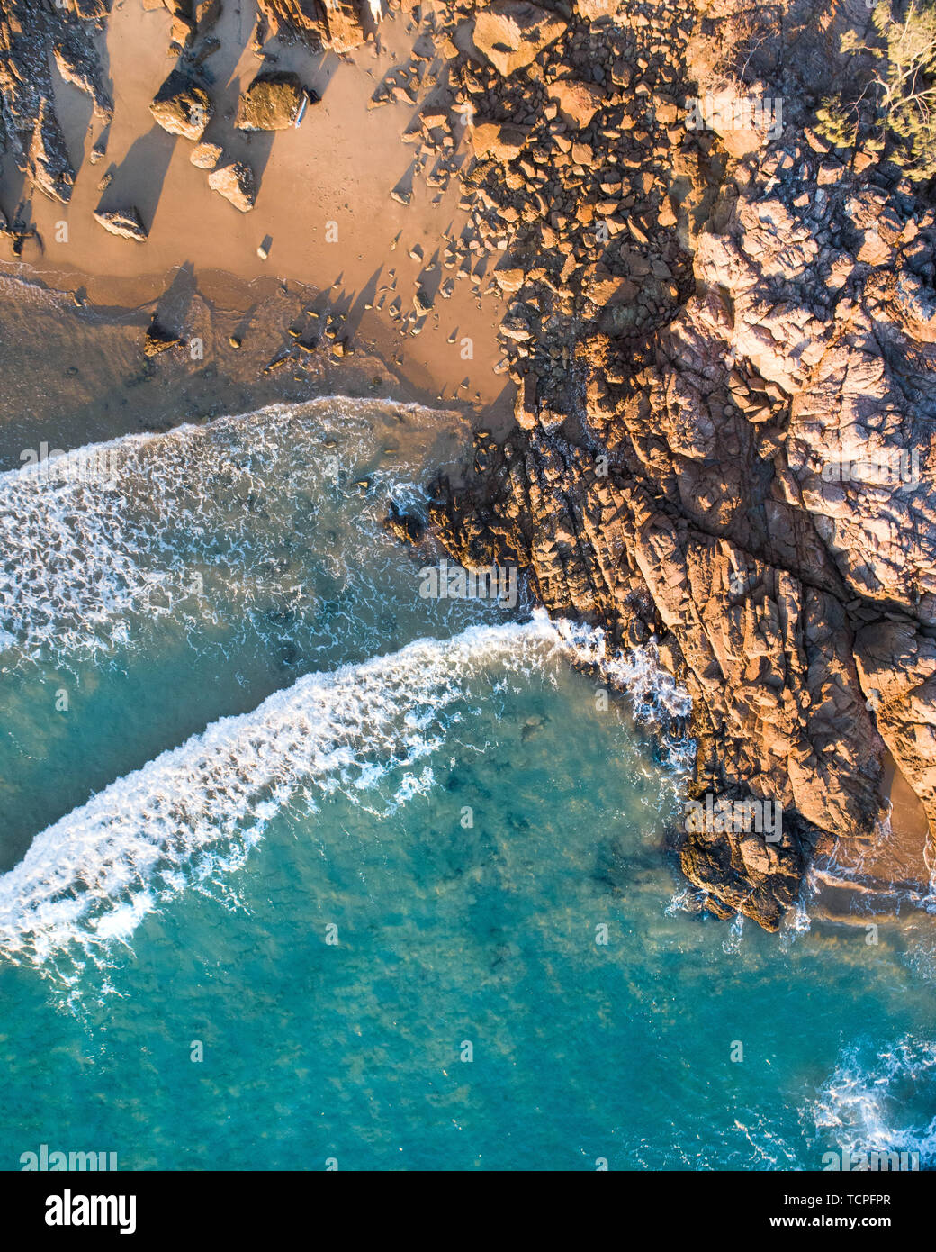Schöne Luftaufnahme eines Beach Escape mit schönen Strand, Felsen und warmen sanften Wellen. Strand Strand mit weißem Sand und lite Abendrot Stockfoto