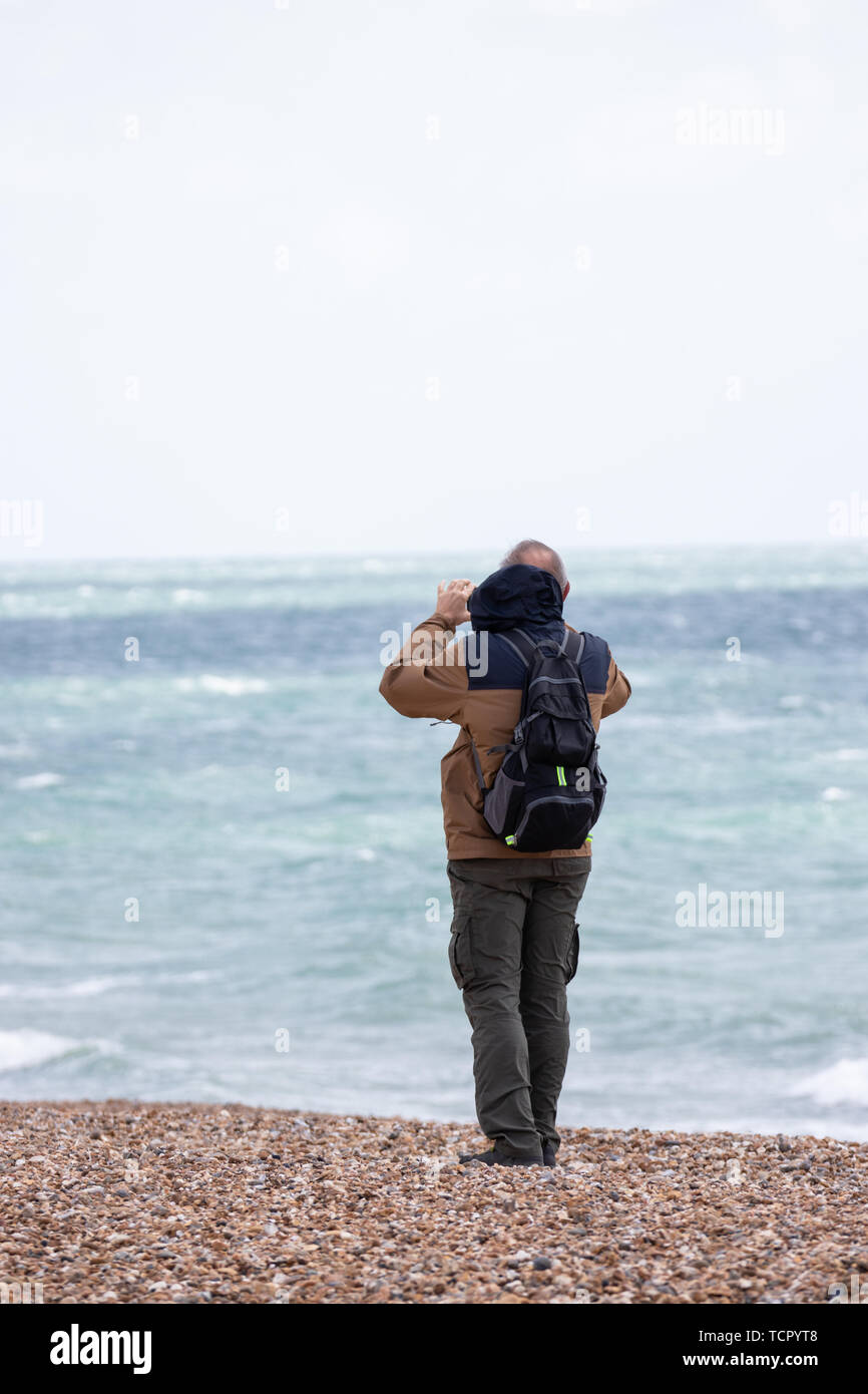 Ein Mann mit seinem Handy oder Handy ein Foto am Meer zu nehmen Stockfoto