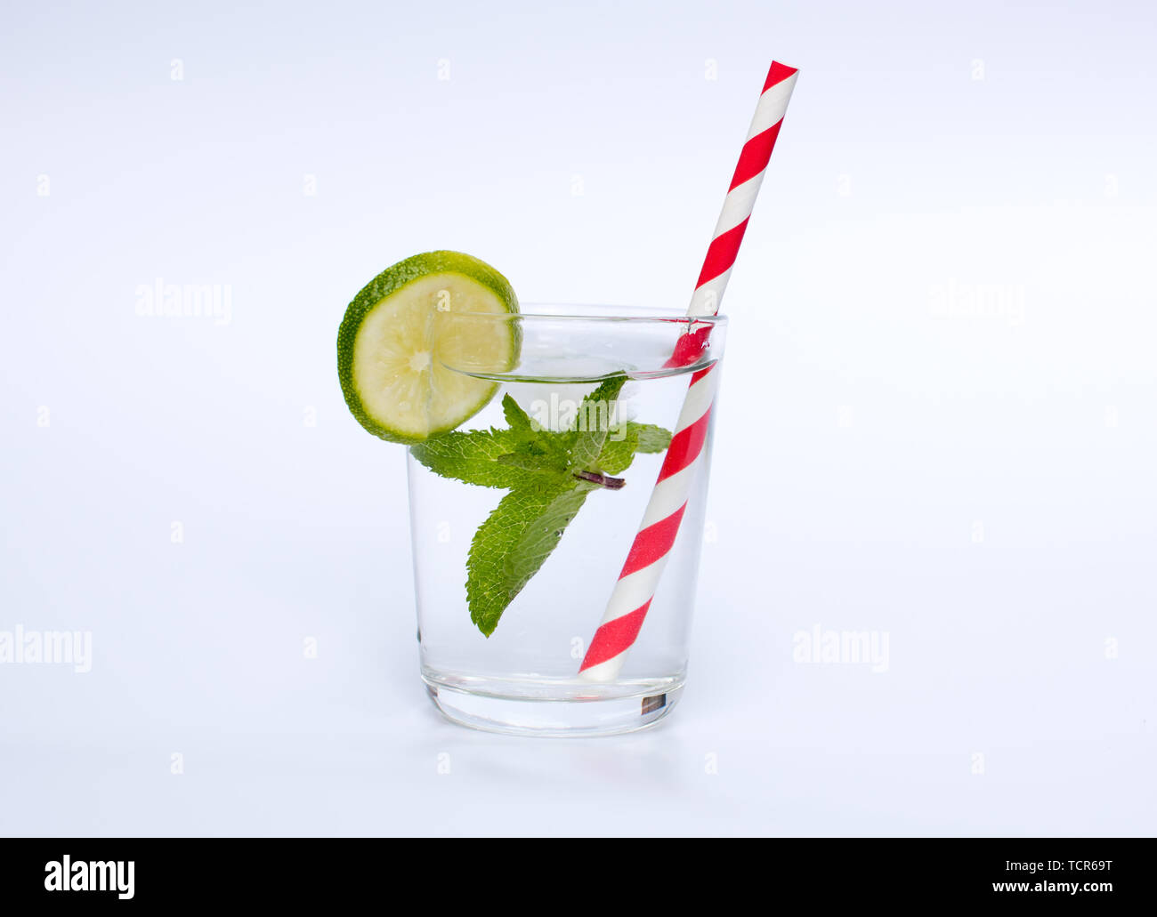 Eine transparente Drink in ein kleines Glas demonstriert die Verwendung von Papier, Stroh auf weißem Hintergrund Stockfoto