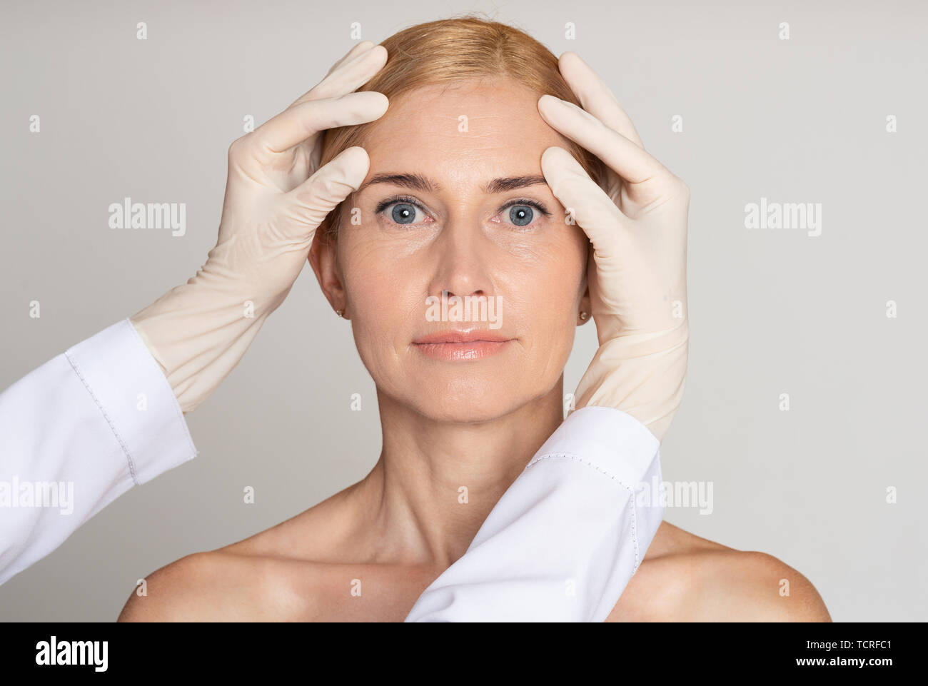 Kosmetische Chirurgie Konzept. Arzt untersuchen, reife Frau Gesicht Stockfoto