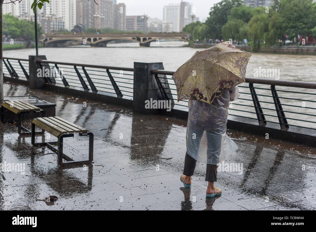 Chengdu, Provinz Sichuan, China - Juli 11,2018: Mann mit Schirm beobachten Jinjiang Fluss in der Flut nach starkem Regen in der Provinz Sichuan. Stockfoto