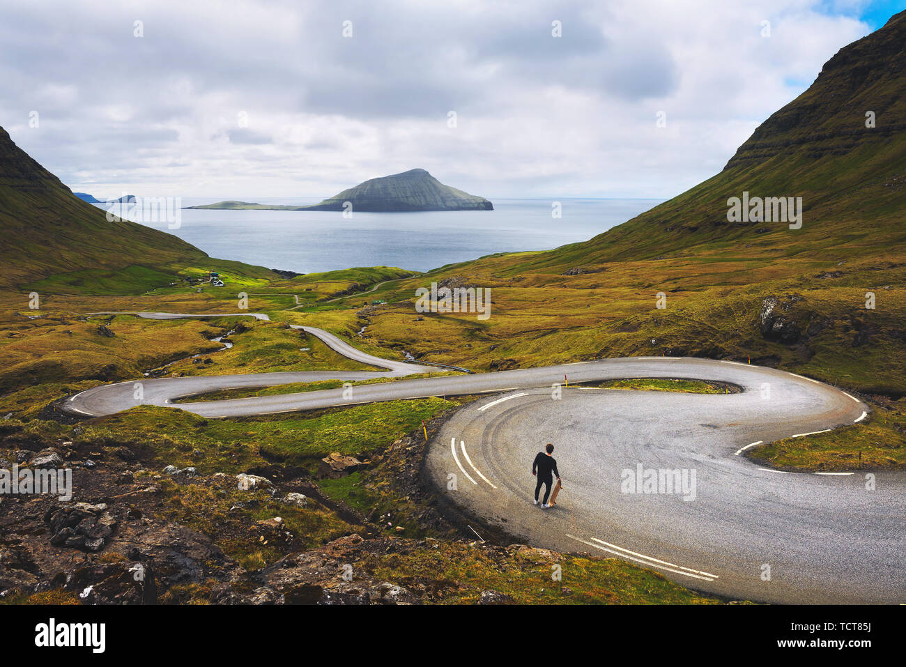 Jungen Skater mit seinem Skateboard schaut auf die wunderschöne Landschaft der Färöer Inseln Stockfoto