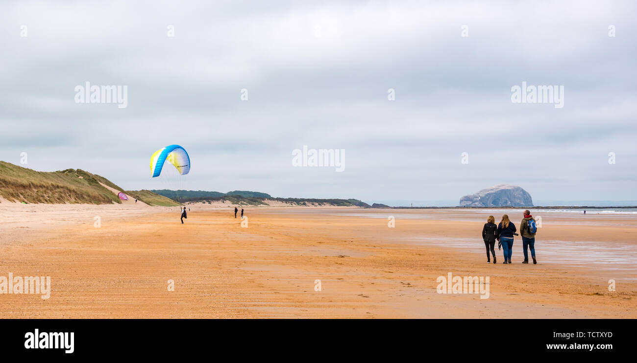 Tyninghame Strand, East Lothian, Schottland, Vereinigtes Königreich, 10. Juni 2019. UK Wetter: Nicht ganz genug Wind ein Gleitschirm mit einem Flügel Drachen in der Luft auf die Weite der Sandstrand bei Ebbe mit Menschen zu Fuß auf den Strand und Bass Rock gannet Kolonie am Horizont erhalten Stockfoto