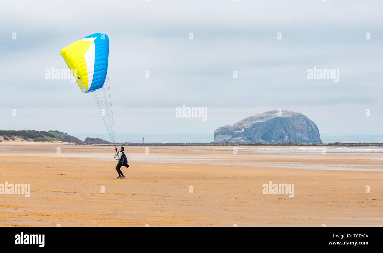 Tyninghame Strand, East Lothian, Schottland, Vereinigtes Königreich, 10. Juni 2019. UK Wetter: Nicht ganz genug Wind ein Gleitschirm mit einem Flügel Drachen in der Luft auf die Weite der Sandstrand bei Ebbe mit dem Bass Rock gannet Kolonie am Horizont erhalten Stockfoto