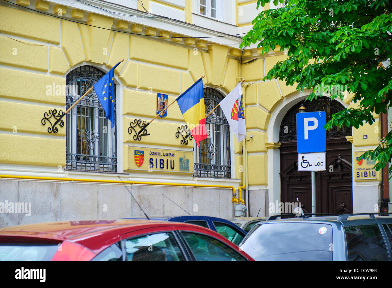 Sibiu, Rumänien, 27. Mai 2019: Sibiu County Council (consiliul Judetean Sibiu) Gebäude - Außenansicht bei Tag, mit Flaggen von Rumänien, der Europäischen Uni Stockfoto