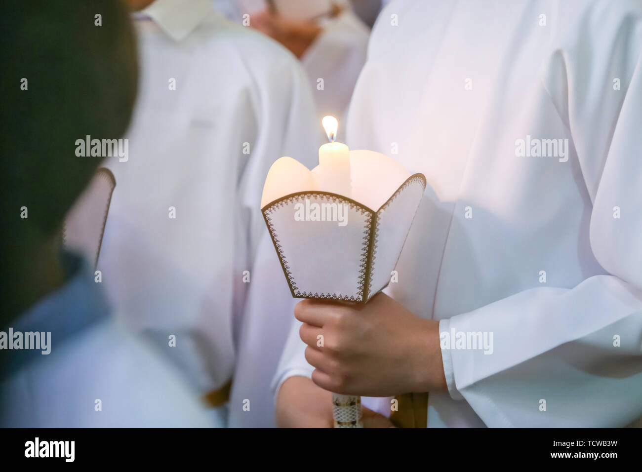 Kinder auf die erste heilige Kommunion in der Kirche. Detail der Kinder, die die brennende heilige Kerze während der ersten Kommunion Masse. Stockfoto