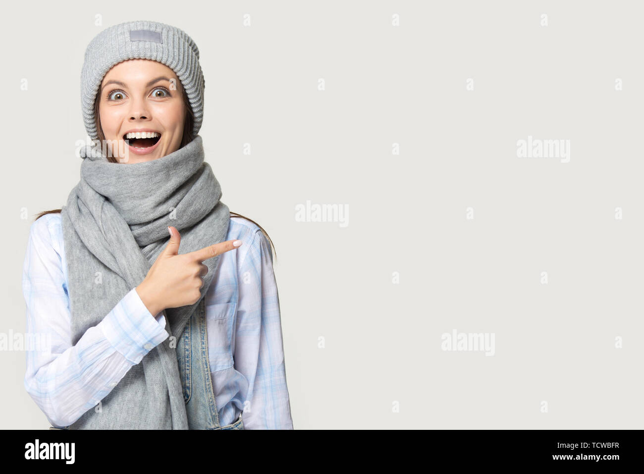 Mädchen mit Strickmütze warme Schal Zeigefinger an Copyspace Stockfoto