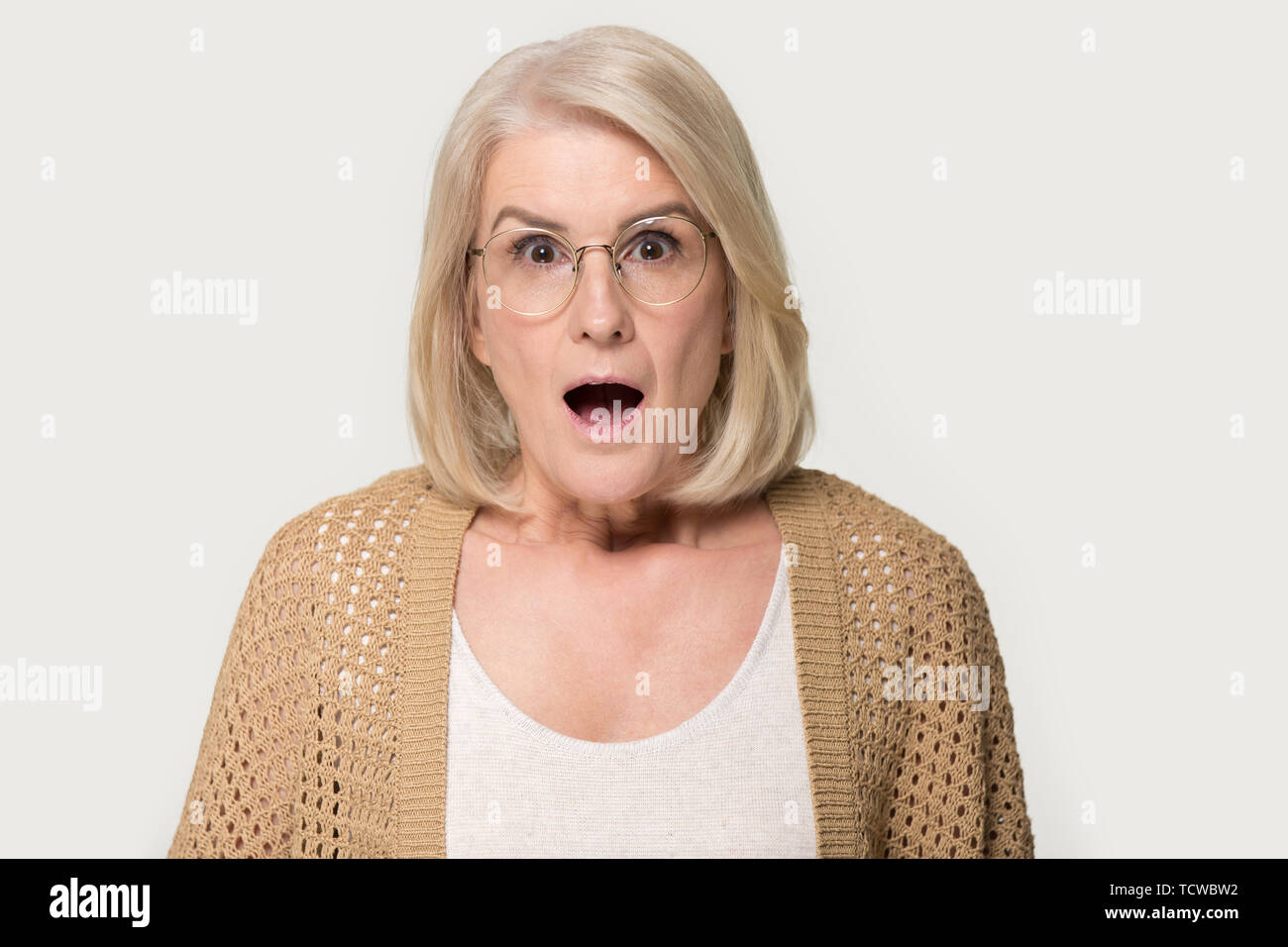 Headshot studio portrait Alter überrascht, schockiert Frau isoliert auf Grau Stockfoto