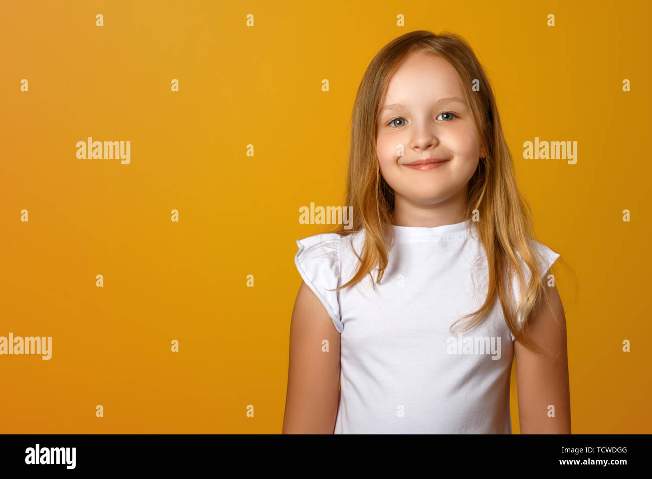 Porträt eines niedlichen kleinen Mädchen auf einem gelben Hintergrund. Ein Kind blond lächelt und schaut in die Kamera. Kopieren Sie Platz. Stockfoto